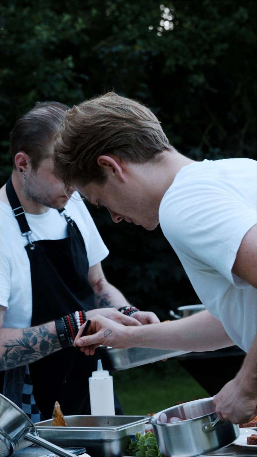 Twee koks werken geconcentreerd aan de mise-en-place op locatie