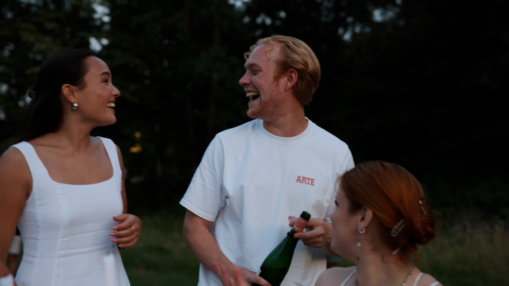 Gasten in het wit met een glas tijdens een feestelijk diner in de buitenlucht