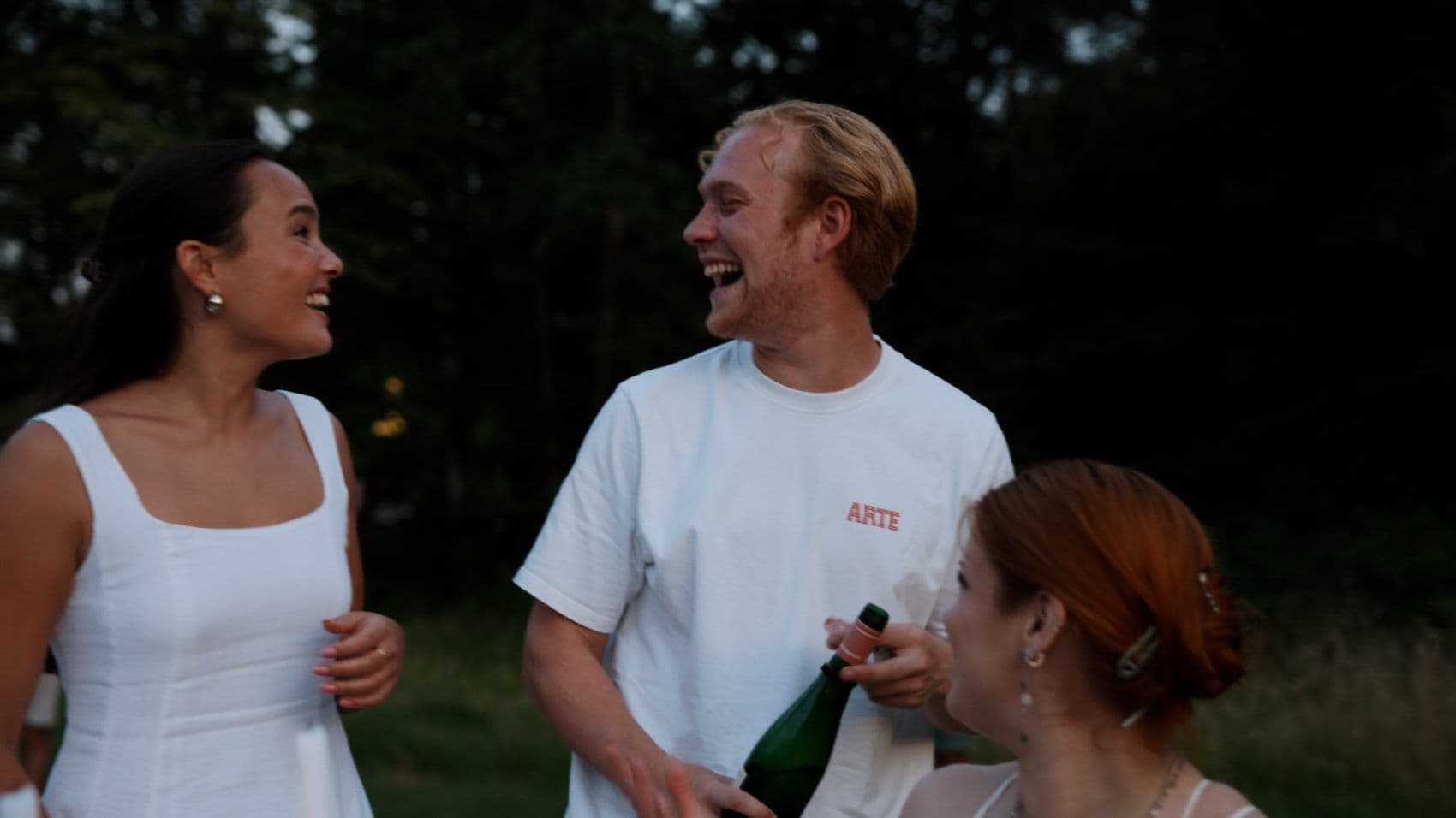 Gasten in het wit met een glas tijdens een feestelijk diner in de buitenlucht